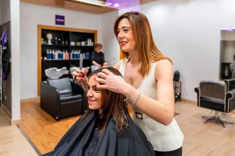 Professional female hairdresser styling a client's wet hair with a comb and hands, preparing for a