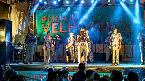 Music band in traditional dress on illuminated stage during evening performance, a band plays and