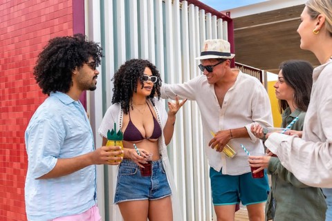 Group of diverse friends is standing outdoors, drinking refreshments and enjoying a cheerful summer