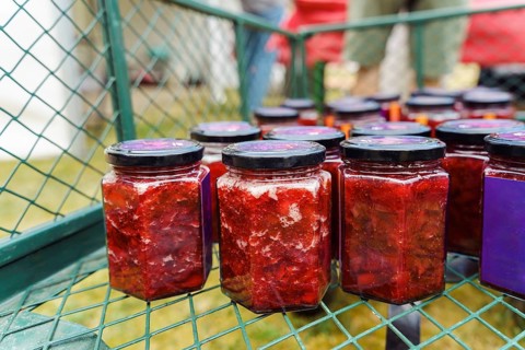 Jars with homemade strawberry jam or preserves. Contents are bright red, with chunks of fruit in