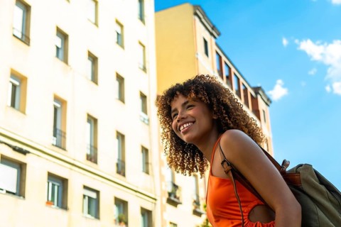 Young black woman with curly hair feeling happy and smiling, enjoying her urban travel adventure