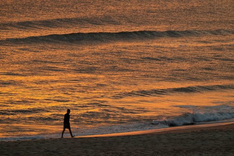 Walkers on the beach, setting sun colors the sea and waves golden, Houvig Beach, North Sea, Denmark