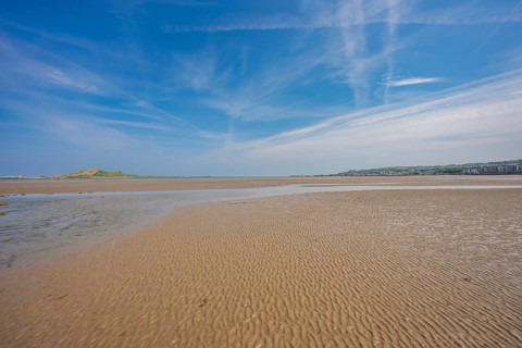 Wide sandy coastline with clear sky and clouds, low tide, Howth Beach, Ireland