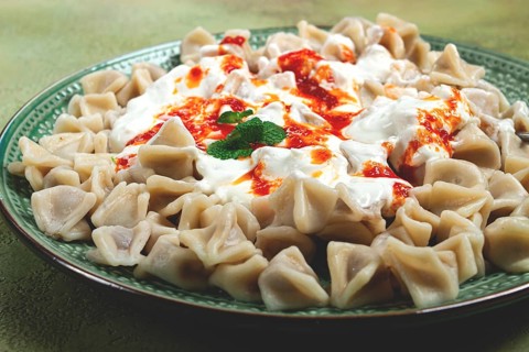 The dish features a generous serving of Turkish dumplings topped with velvety yogurt and a drizzle