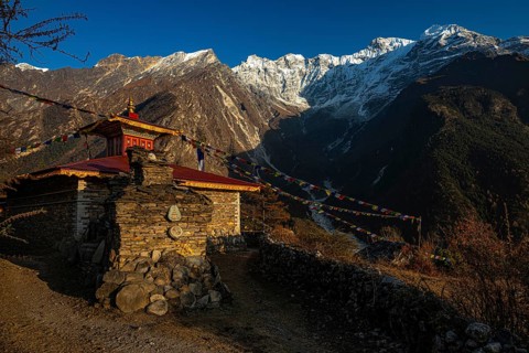 Small Buddhist monastery with manistones in the evening light in front of snow-capped mountains of