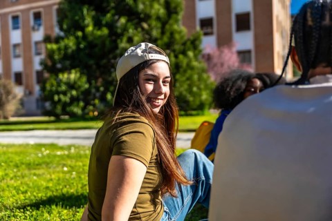 Diverse group of university students interacting and enjoying time together on the green grass of