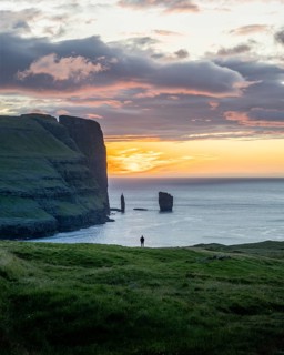 Person on a rock edge off the coast near Gjogv, Faroe Islands