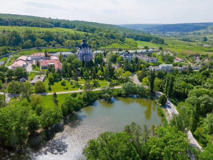 Landscape view with calm lake, hills and a cathedral on the horizon surrounded by green nature,