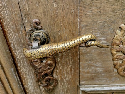 Artfully designed brass or bronze door handle in the shape of a snake or a mythical creature with