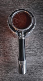 Freshly pressed coffee powder in a portafilter, on a textured wooden table, portafilter of an