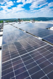 Worker on a large solar system roof in a countryside area, blue sky, PV installation, Perrot