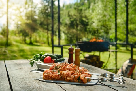 Marinated chicken skewers with vegetables on wooden table in garden. Grilling equipment in