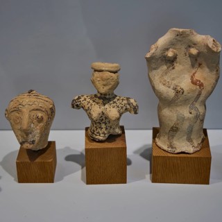 Three ancient ceramic figures from Phylakopi exhibited on wooden bases in a museum, Plaka