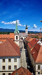 View from Lotrscak Tower, panoramic view of a city with red roofs, a church tower and a clear blue