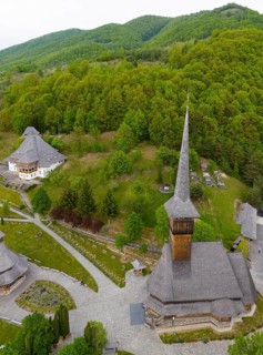 Rural complex with characteristic church towers against a dense forest backdrop, aerial view,