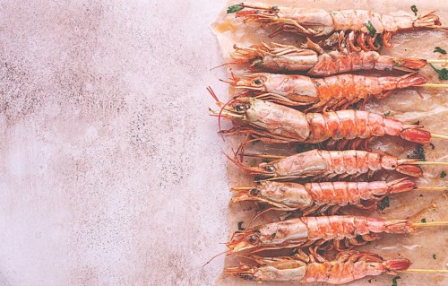 Shrimp on skewers, grilled, laid out on the table, top view