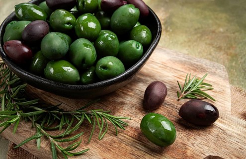 Chalkidiki olives, classic Greek green olives, in a bowl on a cutting board, top view, without