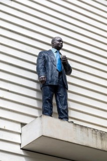 Man with Cup artwork painted bronze sculpture by Sean Henry 2017 black male standing on ledge,