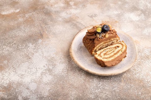 Sweet loaf with cream and caramel, on brown concrete background, copy space, side view