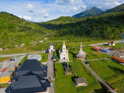 Church complex in a green landscape with mountains in the background, sunny sky with clouds, aerial