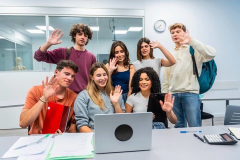 Group of young diverse students in a modern classroom actively participating in an online class or