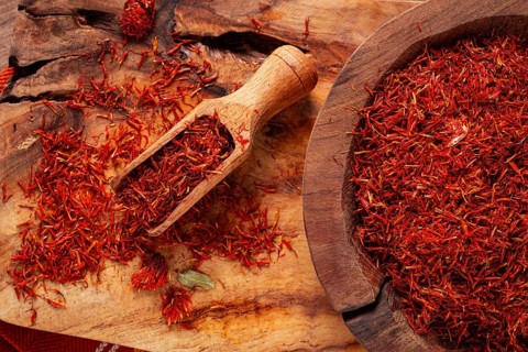 Spice saffron threads, in a wooden bowl, on a wooden table, top view, close-up