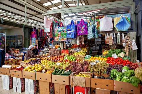 Covered stand with a variety of fruits and vegetables and colorful shopping bags, The Calama market