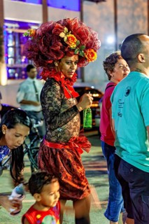 Woman wearing a flashy flower hat standing in a nocturnal crowd, visitor to a festival in Petrolina