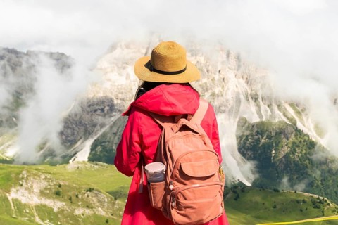Close up asian female hiker with backpack and straw hat looking at misty mountain peaks deep valley