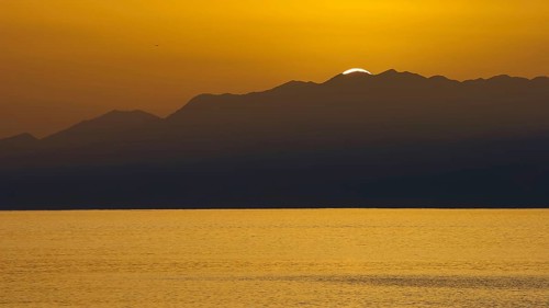 Sunset over sea surface with mountain silhouette in background, Matala, South Coast, Crete, Greek