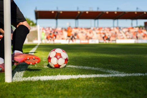Close-up of a player's feet and a soccer ball at the corner arc, ready to perform a corner kick in