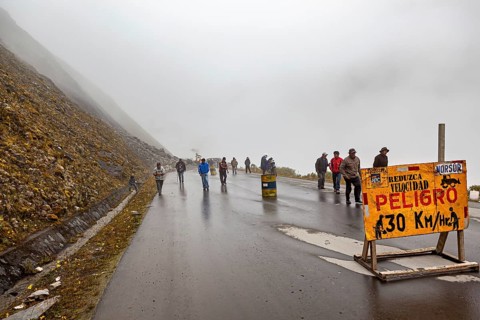 People on a wet fog road, warning road sign for car drivers, rockslide on the pass road towards