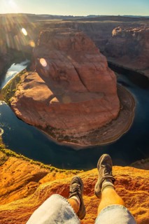Tourist enjoying a stunning sunrise view over the iconic horseshoe bend, with the colorado river