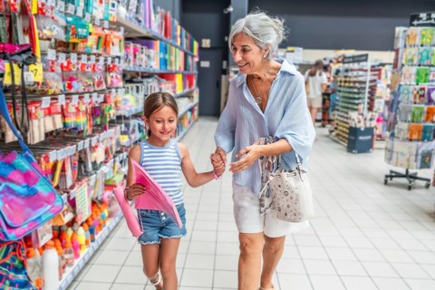 Grandmother and young granddaughter holding hands and smiling, walking down a vibrant aisle in a