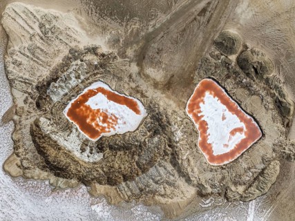 Saline ponds with ruddy algae growth and white salt deposits at the Skeleton Coast. Aerial view.