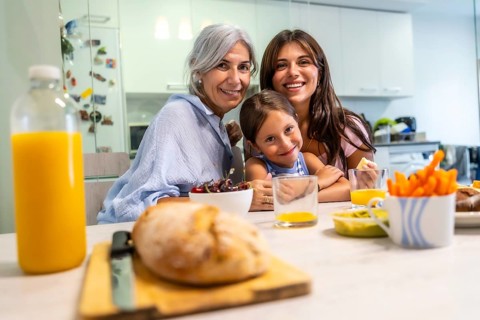 Grandmother, mother, and granddaughter are enjoying a cheerful breakfast together at home, sharing