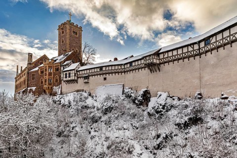 Snow-covered castle with tower and timbering under a cloudy sky, The Wartburg near Eisenach in