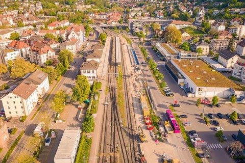 Urban station district with tracks, surrounding buildings and parked buses in summer,
