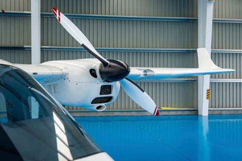 Propeller airplane parked inside a brightly lit aerospace hangar, representing concepts like