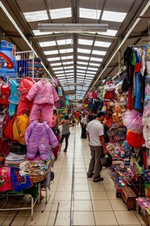 Colourful market alley with a variety of clothes and toys, visitors browse the stalls, The market