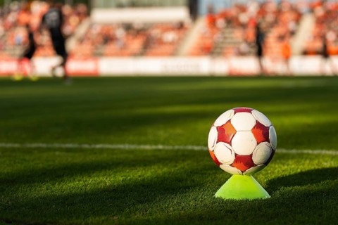 Soccer ball on a training cone near the touchline during a football match with players and stadium
