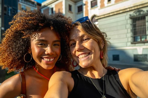 Two happy and diverse young women smiling at the camera for a selfie, celebrating friendship and