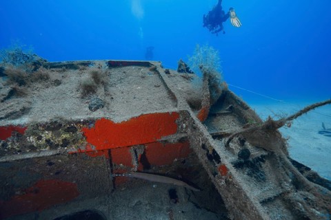 Divers inspecting a rusty part of a sunken ship, meteor wreck dive site, Russian hydrofoil,