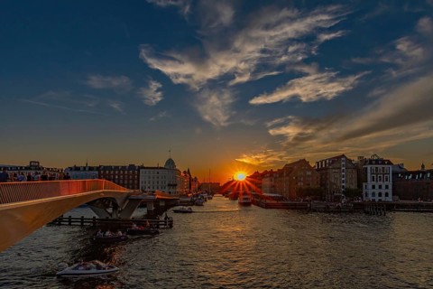 Sonnenuntergang über einem Fluss mit Brücken, Booten und malerischem Himmel, Kopenhagen, Dänemark,