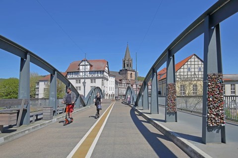 Old Fulda Bridge, bike path with cyclist and e-scooter, steel girder with love locks, church tower,