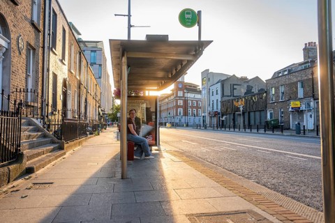 A bus stop at sunset with a person looking at the cityscape, Dublin, Ireland