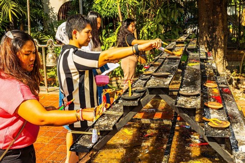 Young Thai and Thai women light incense in the Wat Phra Singh Buddhist temple complex, Chiang Mai