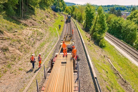 Worker on a rail train in a rural area with surrounding green hills, electrification of the