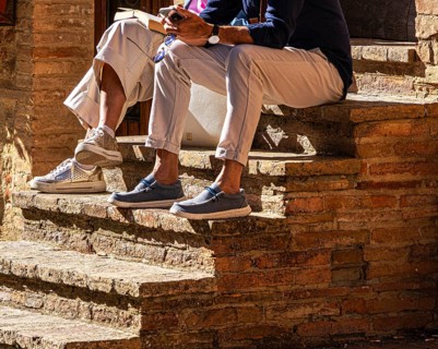 Two tourists sit on the steps of a stone staircase, Pienza in Tuscany, Italy
