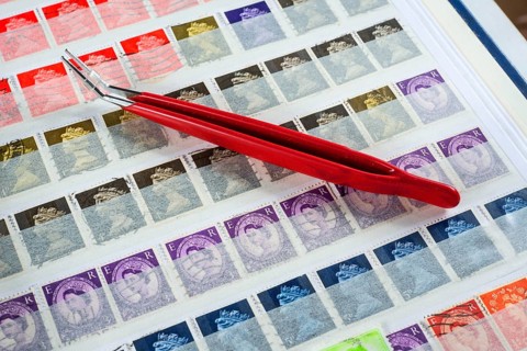 Philately, tweezers on album page with English stamps